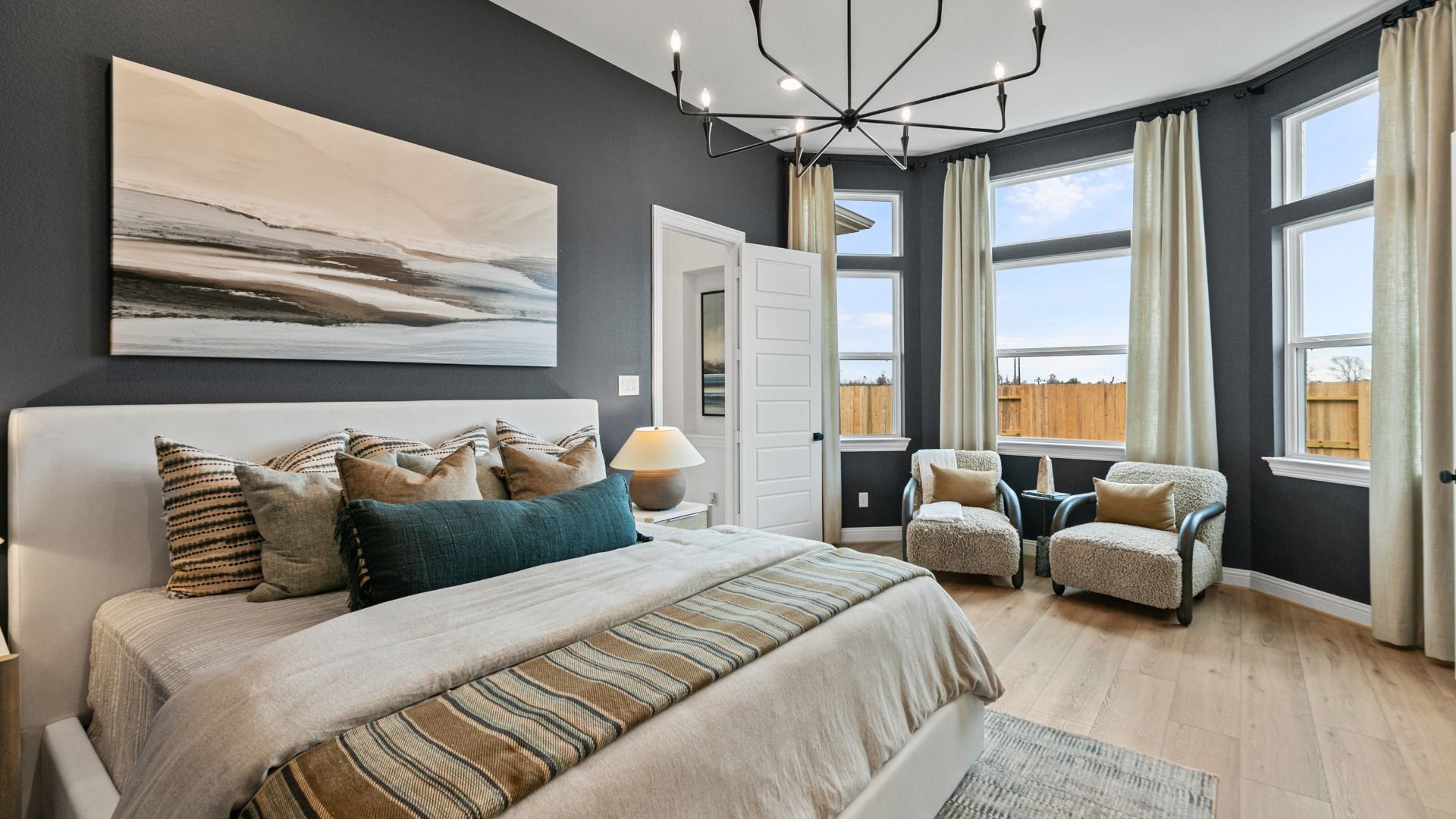 Elegant primary suite in Aldeana combines large windows with a relaxing sitting area.