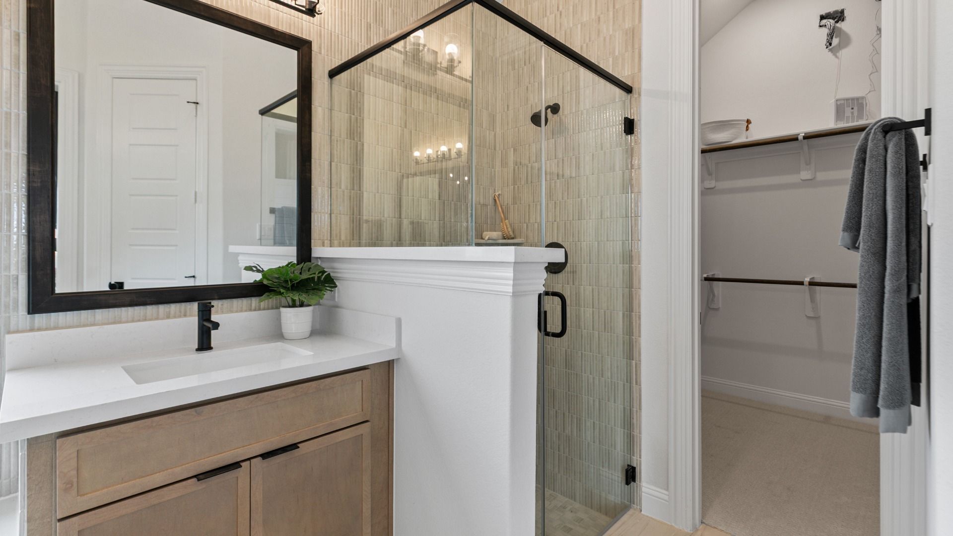 Matte black finishes pair with floor-to-ceiling tile in this stylish bathroom in Aldeana.