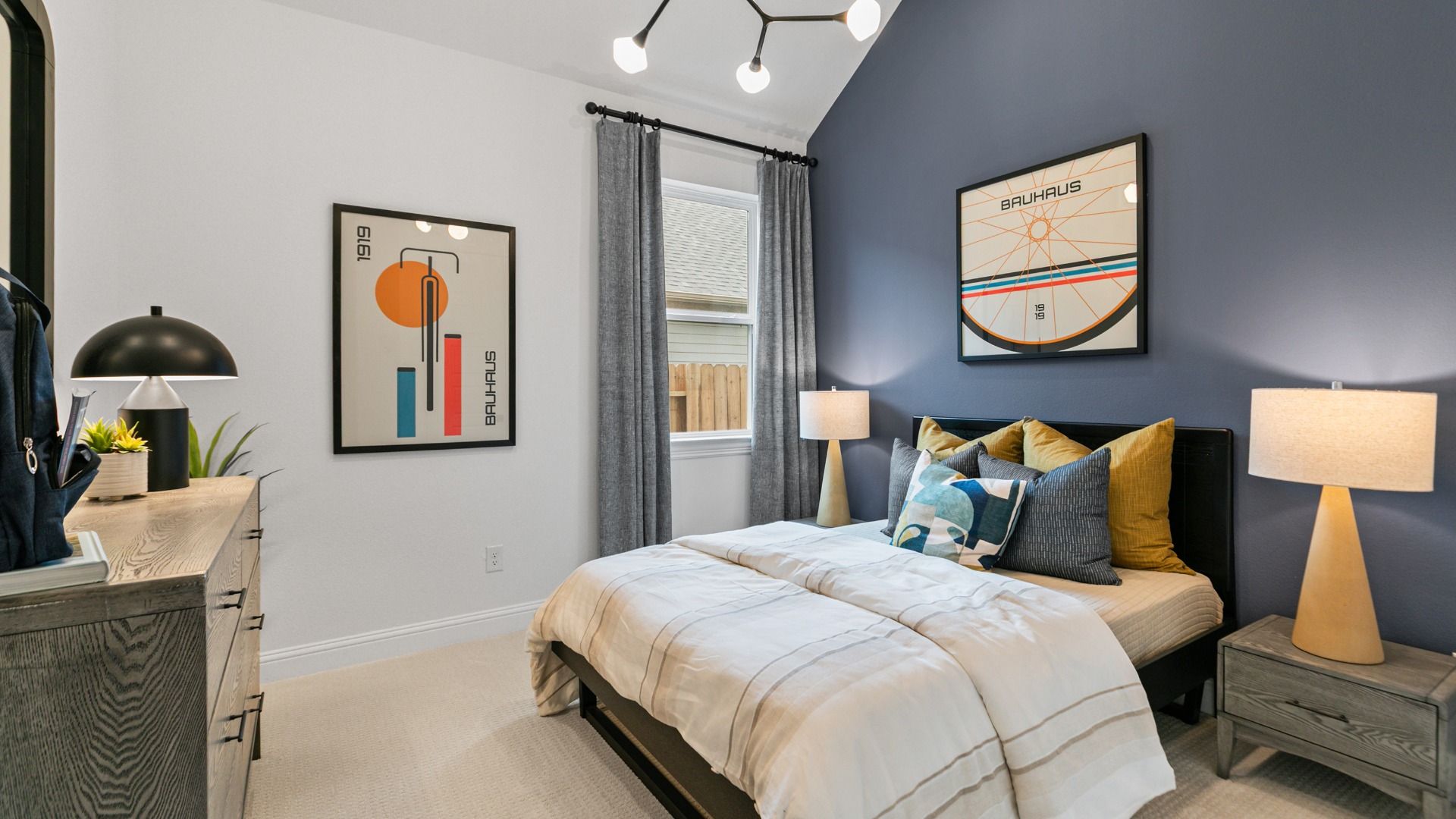 This bedroom in Aldeana features a navy accent wall and bright window.