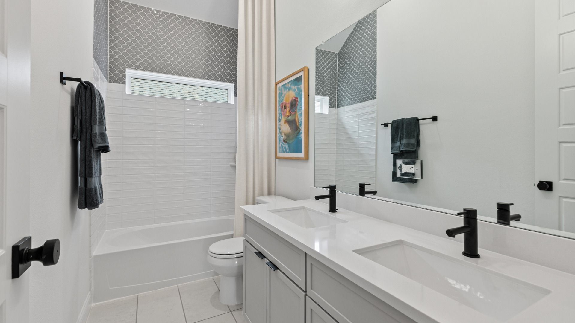 This bathroom in Aldeana features grey and white tiling with bold matte black accents.