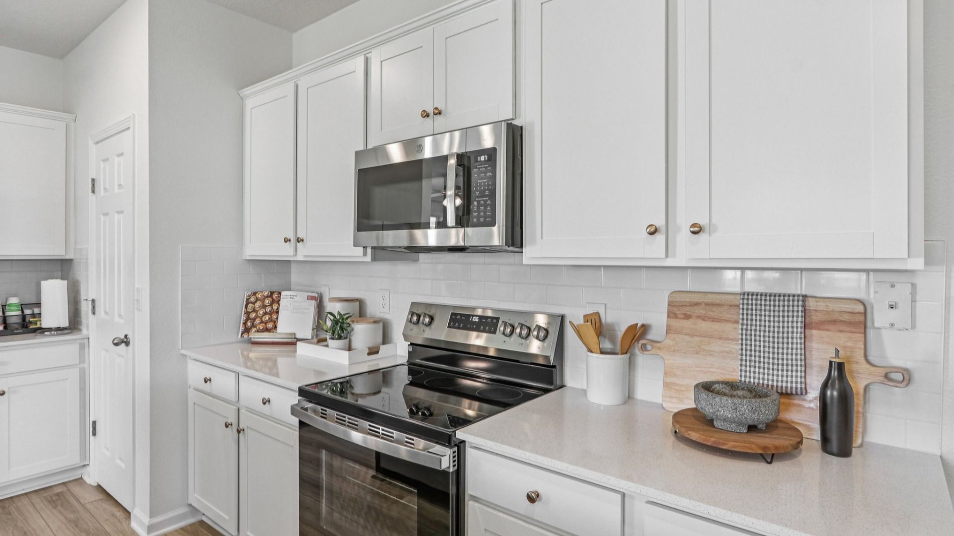 Luxurious kitchen in Panther Creek boasts sleek white cabinetry, marble island, and premium stainless appliances.
