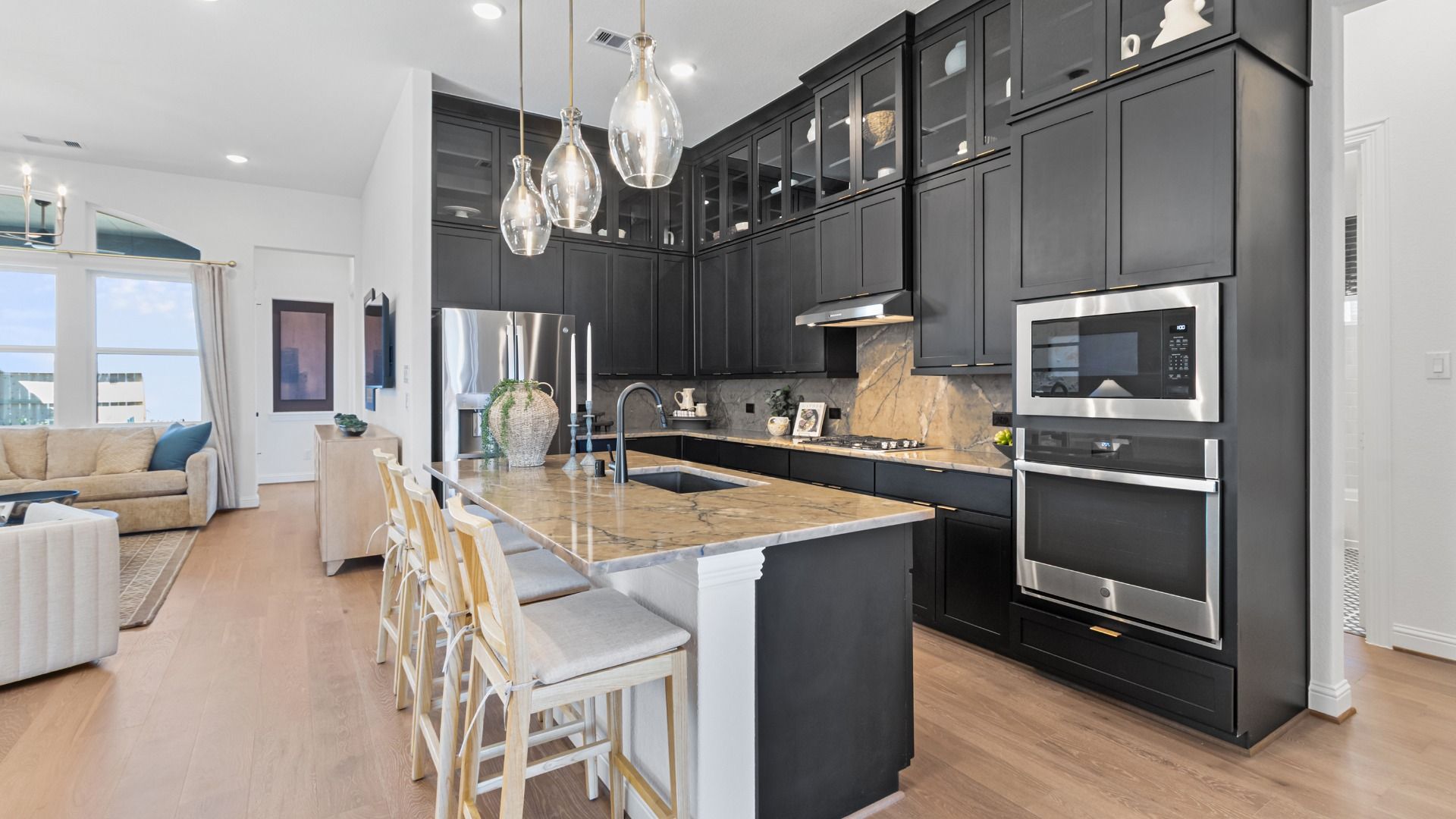 Chic pendant lighting, warm Granite Countertops, and Bold Cabinetry in Wildrye Kitchen