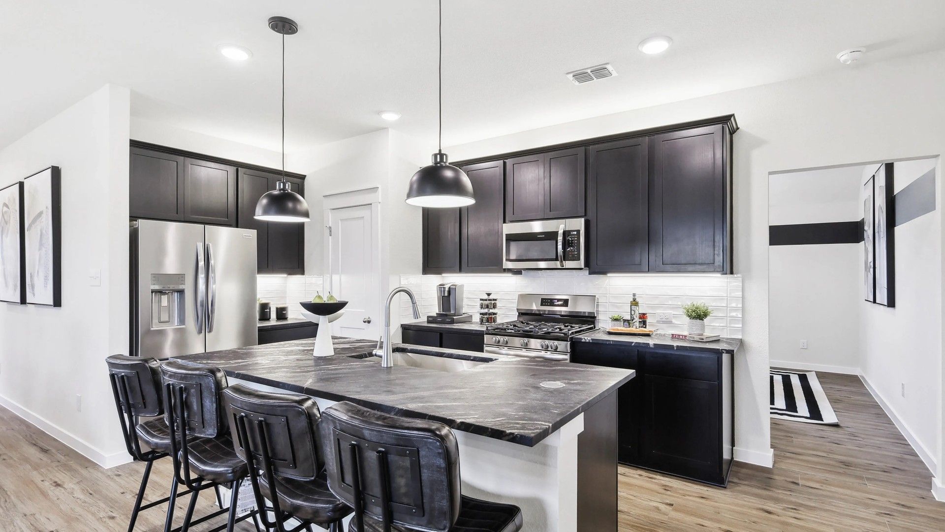 This Simpson Crossing kitchen features sleek dark cabinetry and a refined stone island, blending elegance with functionality.
