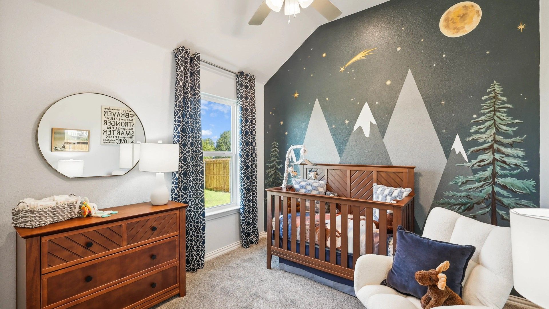 Exquisite nursery with elegant mountain mural and rich wood furnishings in Pebblebrook.