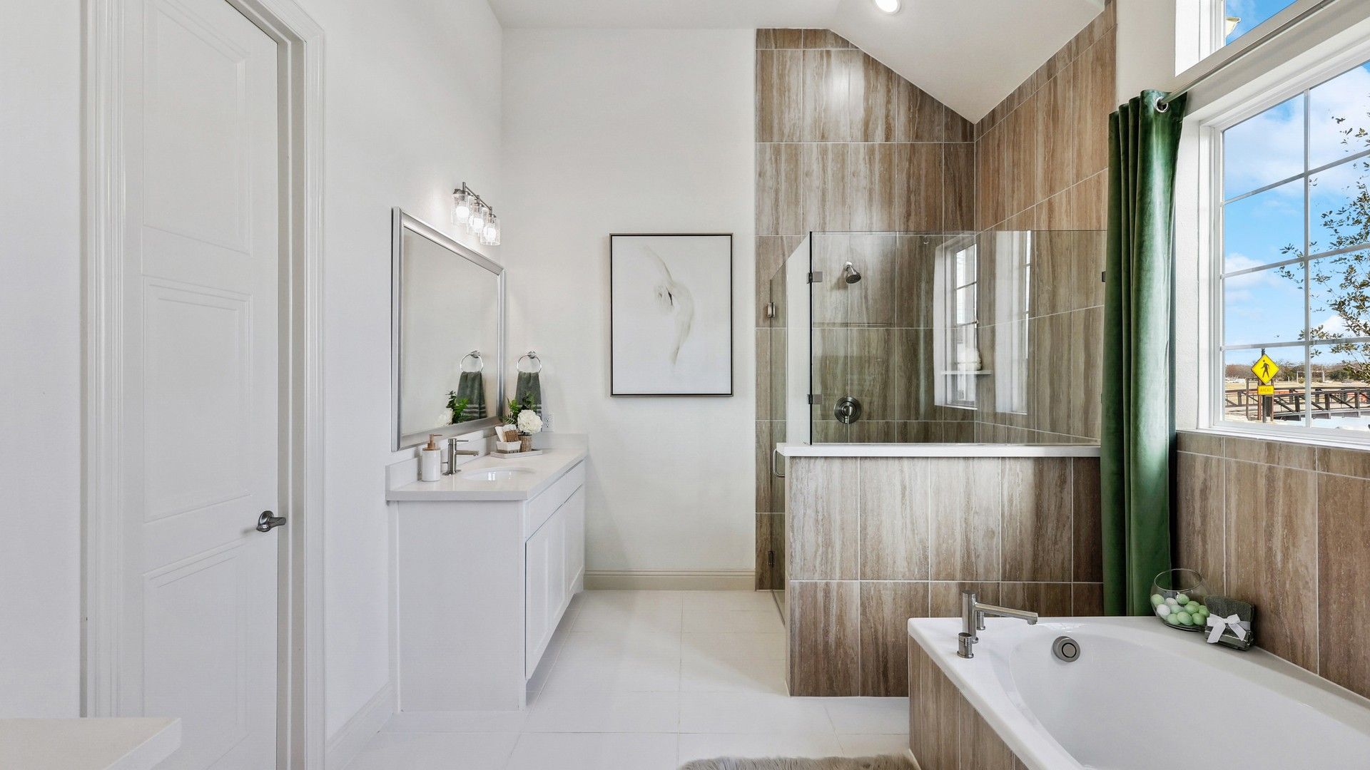 Experience luxury with a glass shower, chic tub, and expansive mirror in Solterra, Texas. Tailored for elegance.