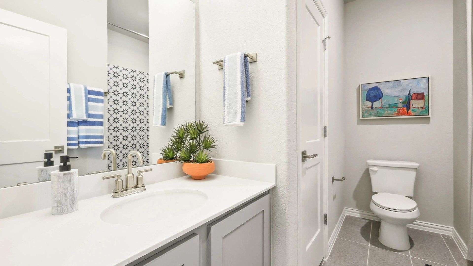 Luxurious white vanity and stylish tiles highlight this Pebblebrook community bathroom.