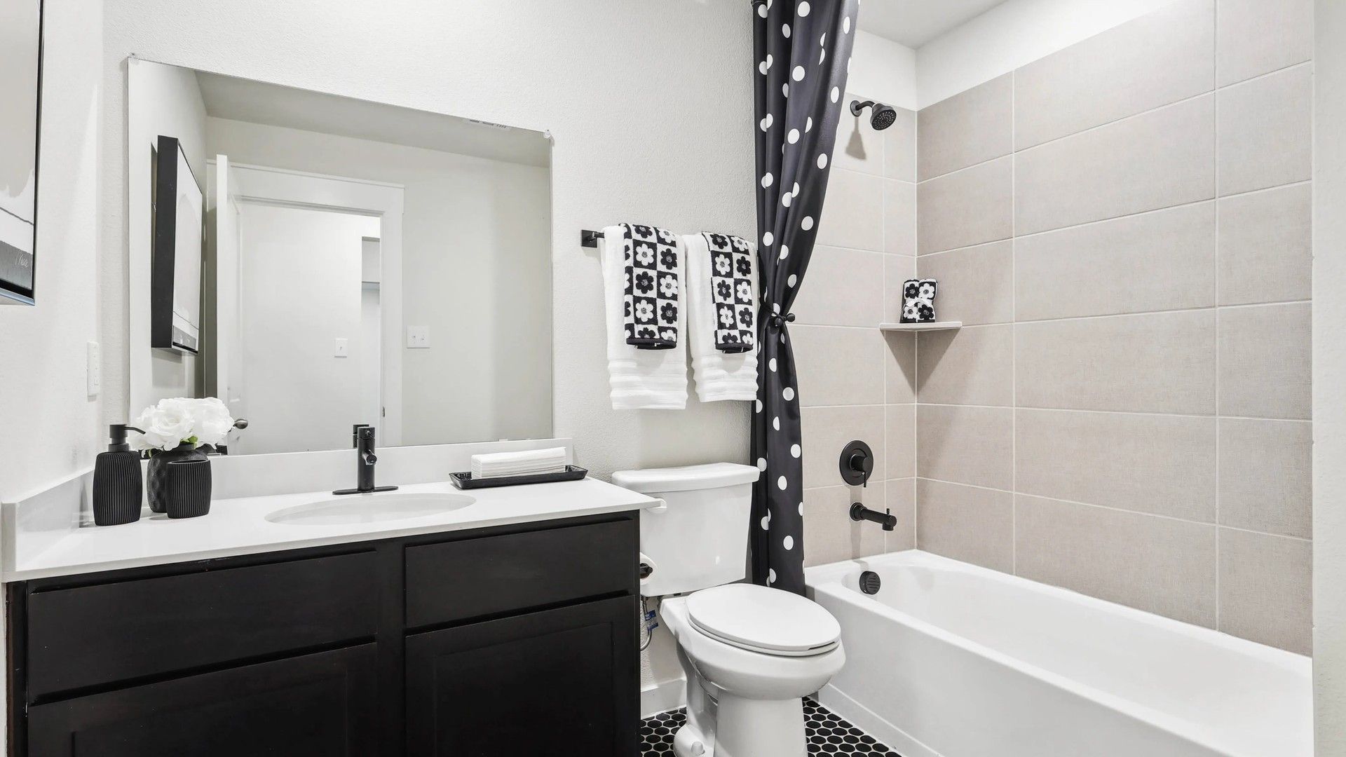 Experience timeless elegance with sleek black vanity and hex tile flooring in Simpson Crossing's luxurious bathroom.