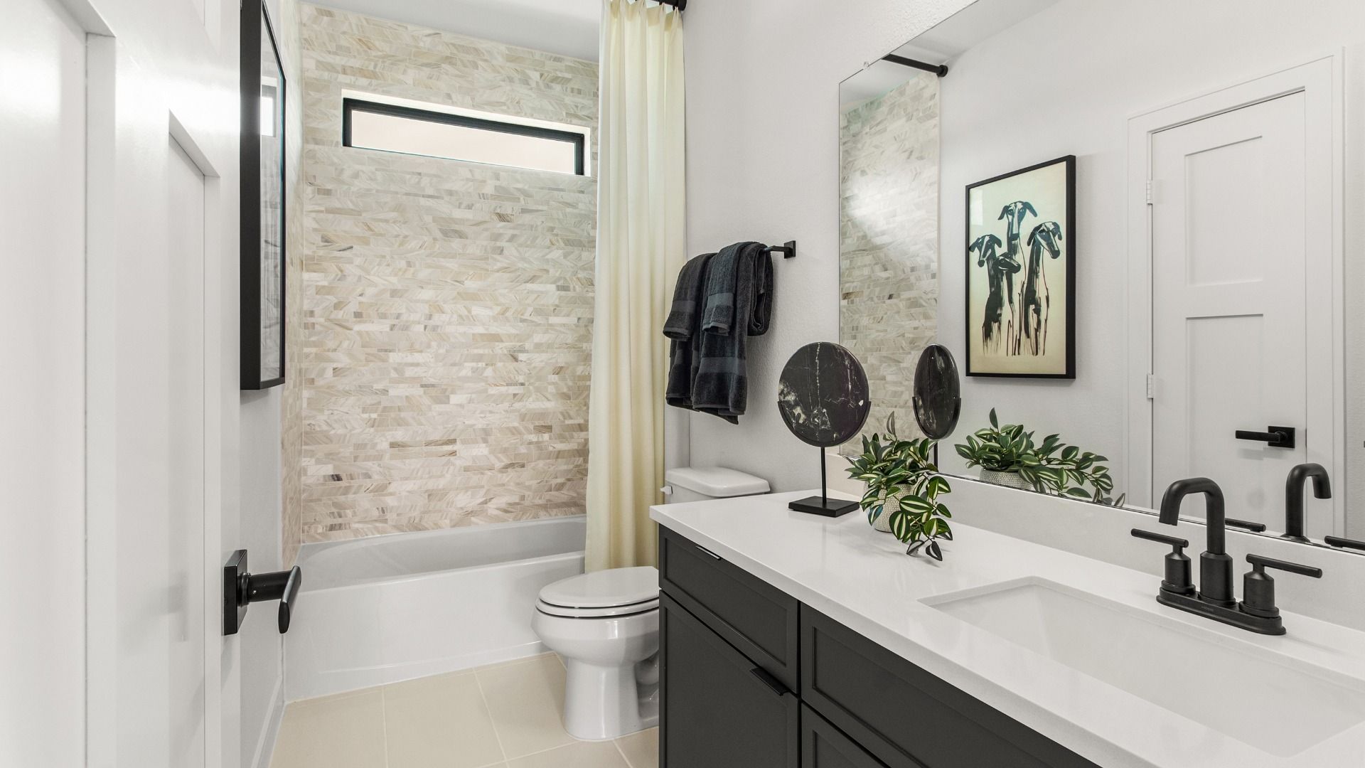 Dark cabinetry and light beige tile create a warm modern bathroom in this Bridgeland Central home.