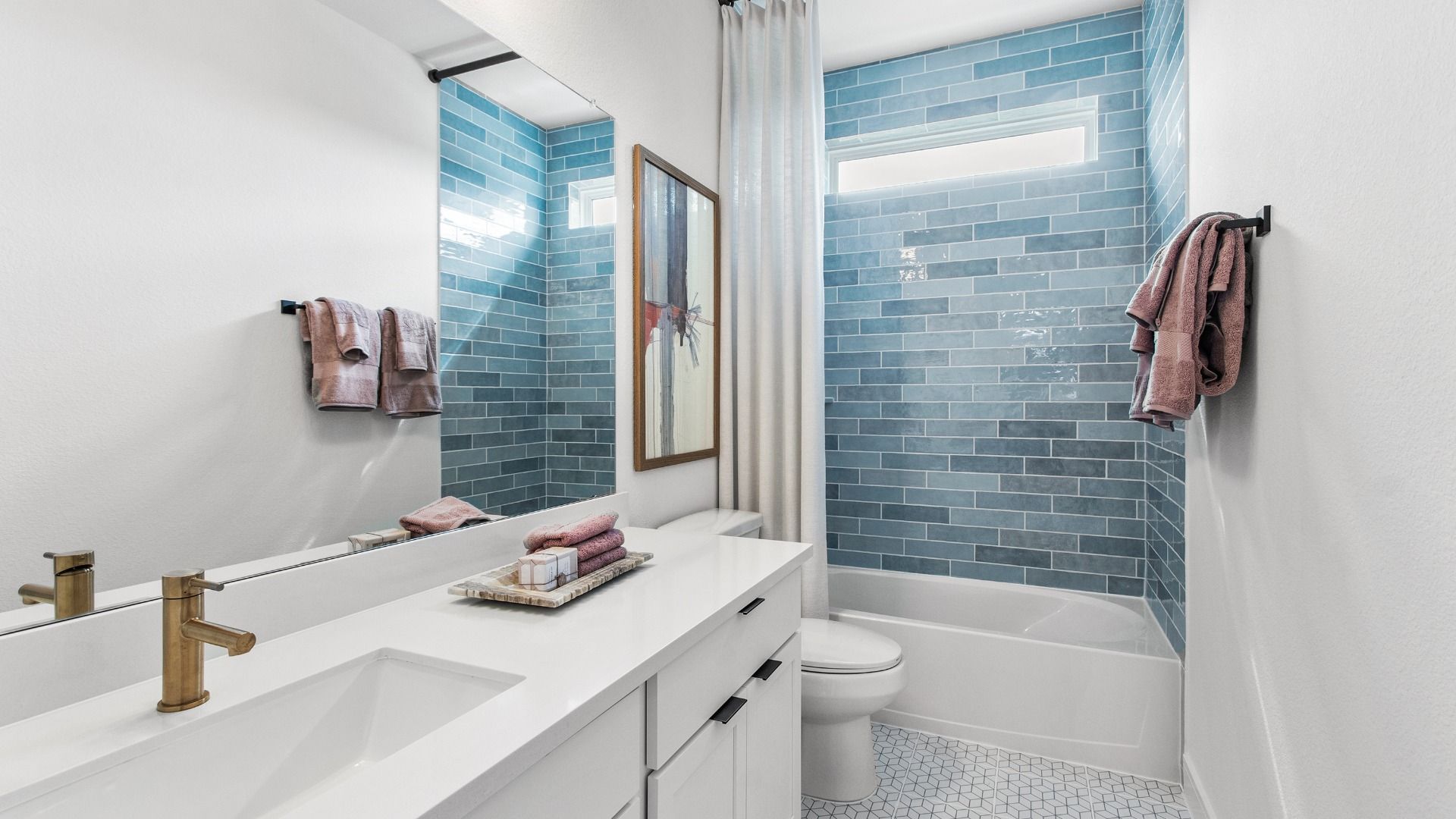 Clean, bright bathroom in Bridgeland Central with blue tile accent design.