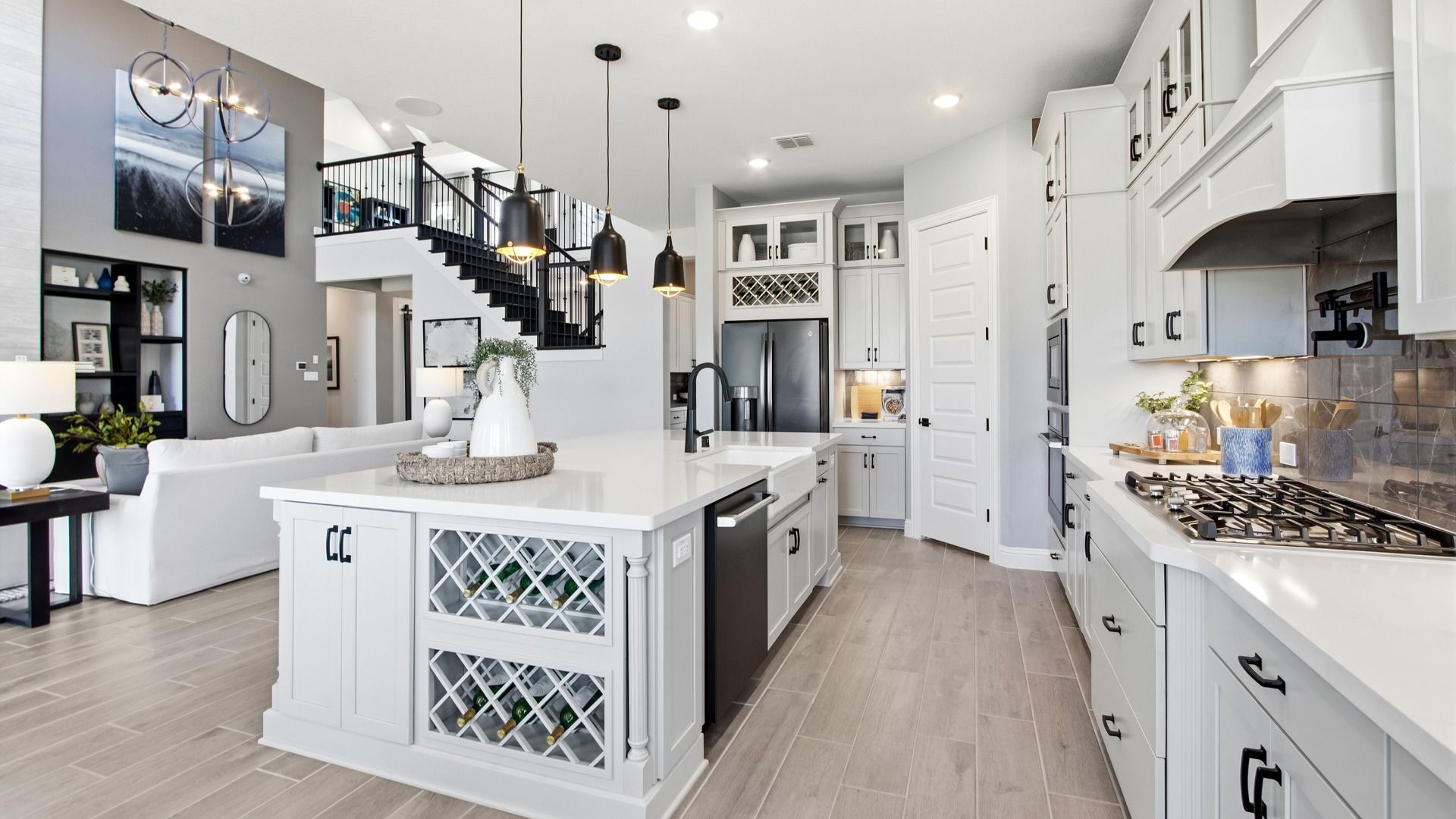 Luxurious kitchen features a sleek white island, sophisticated lighting, and grand staircase at Mostyn Manor Reserve.