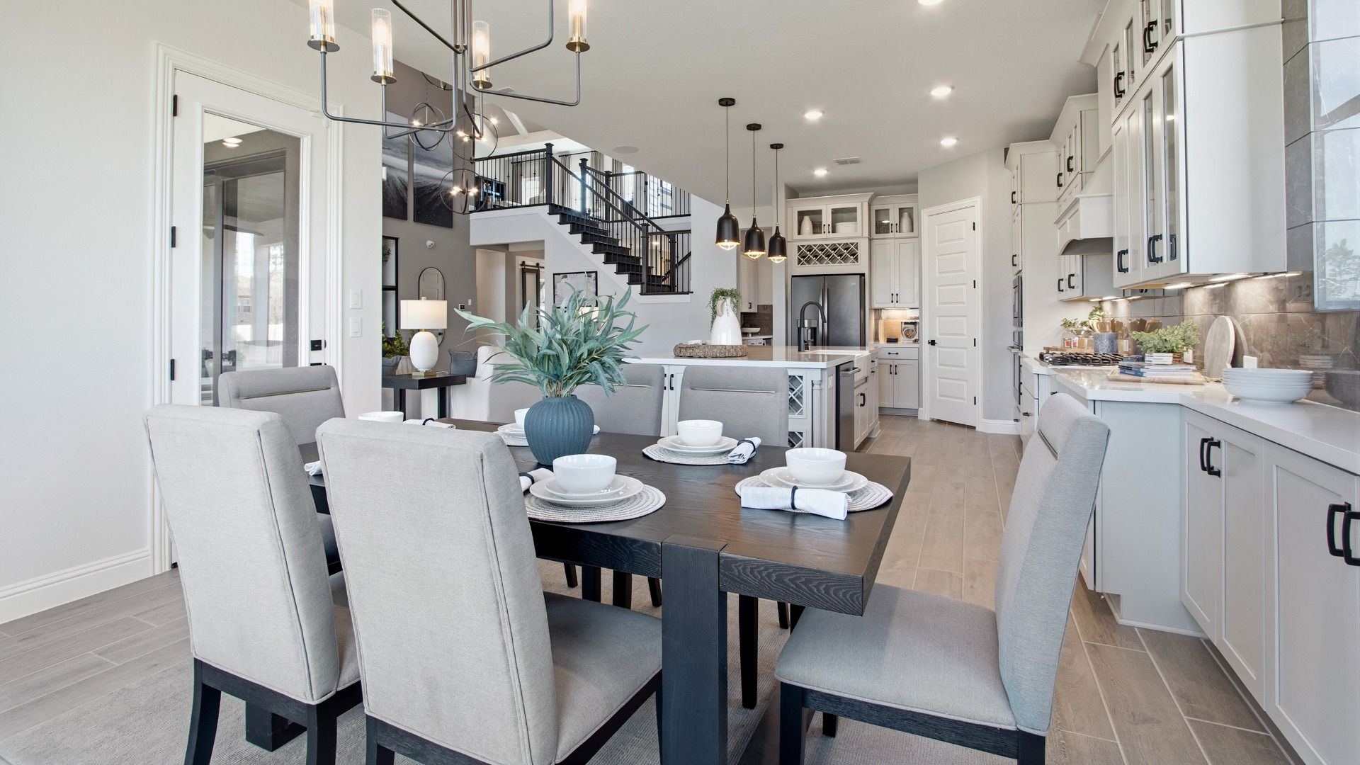 Luxurious dining room features modern chandelier, dark wood table, elegant blue drapery, in Texas estate.