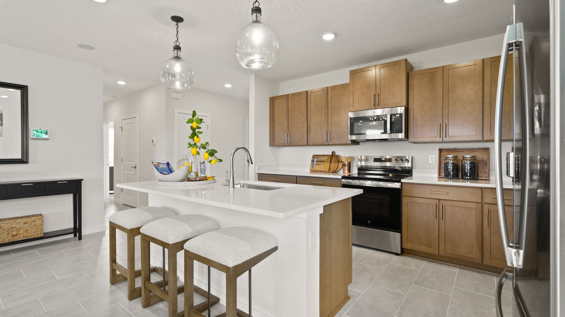 Modern Farmhouse Style Model Home Kitchen open concept Interior by DRB Homes with brown cabinets.