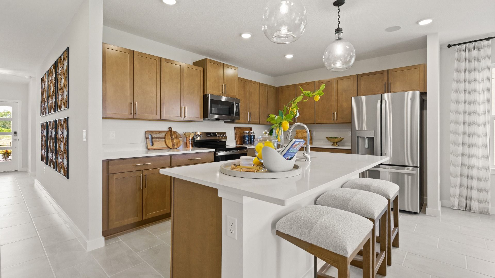 Modern Farmhouse Style Model Home Kitchen open concept Interior by DRB Homes with brown cabinets.