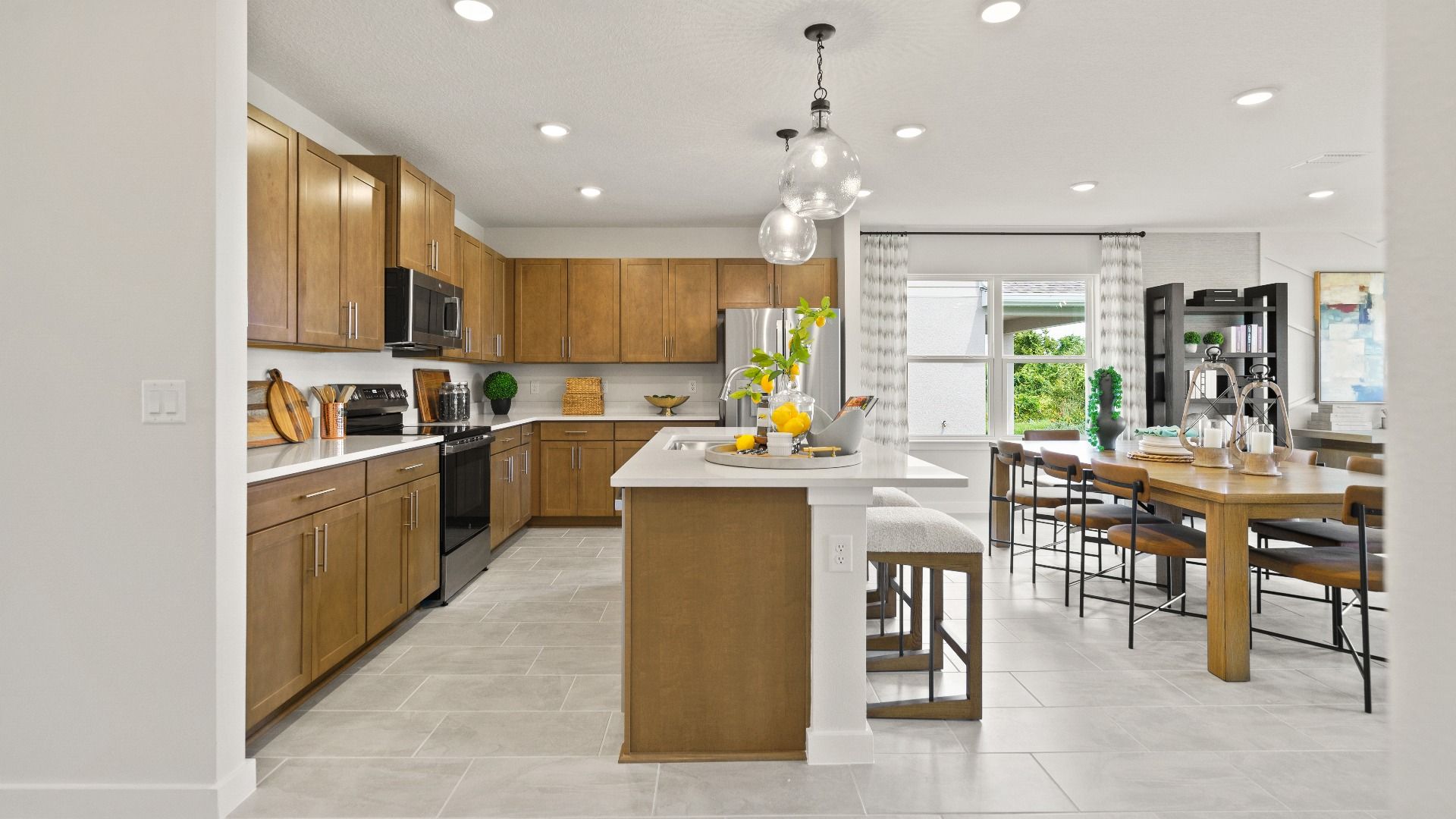 Modern Farmhouse Style Model Home Kitchen open concept Interior by DRB Homes with brown cabinets.