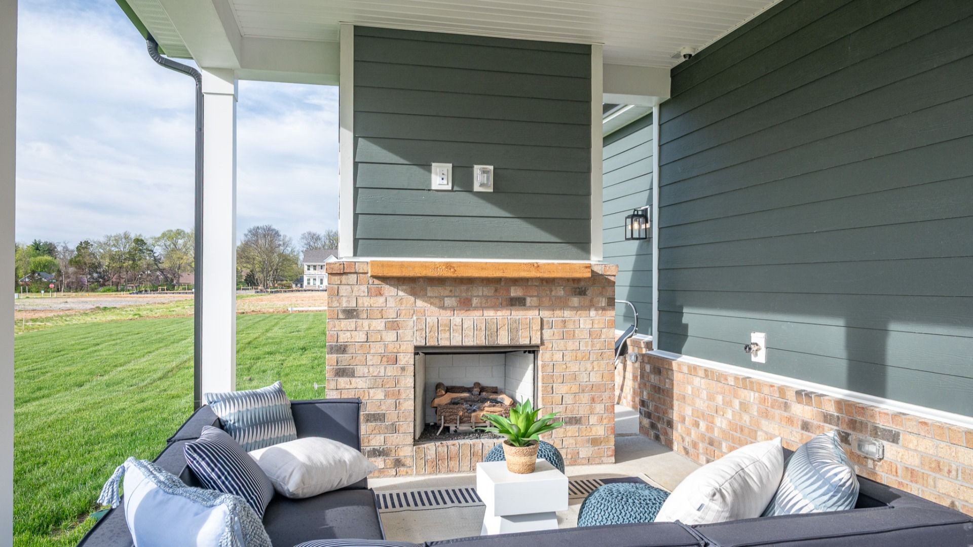Covered outdoor seating area with fireplace and mantel and outdoor sectional