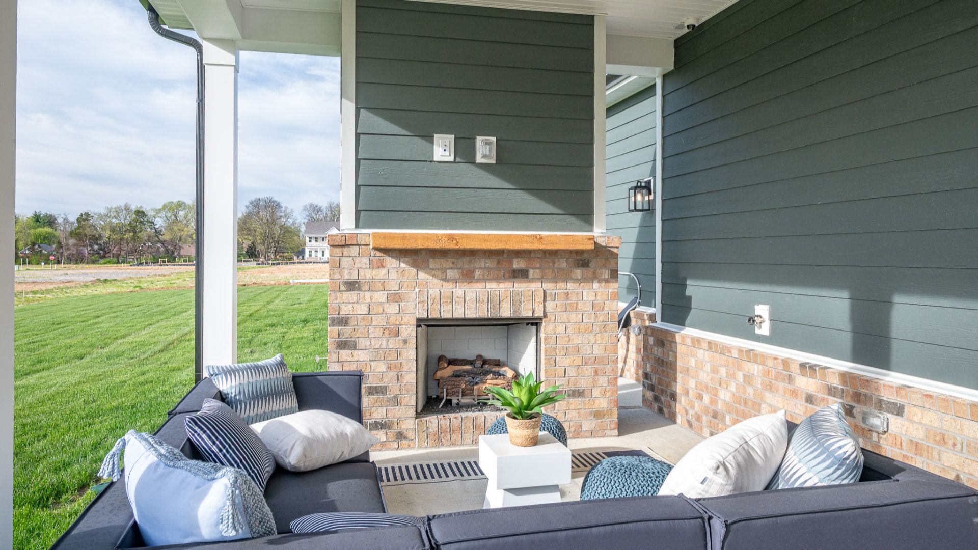 Covered outdoor seating area with fireplace and mantel and outdoor sectional