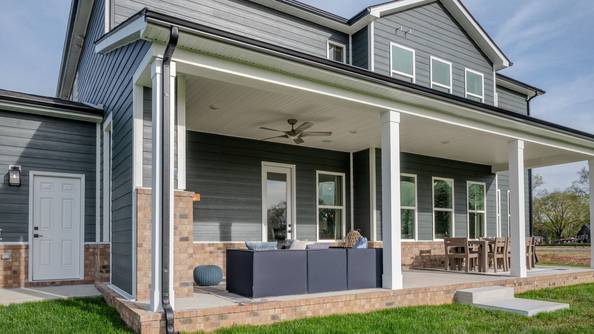 Covered outdoor seating area with fireplace and mantel, outdoor sectional, and outdoor dining area