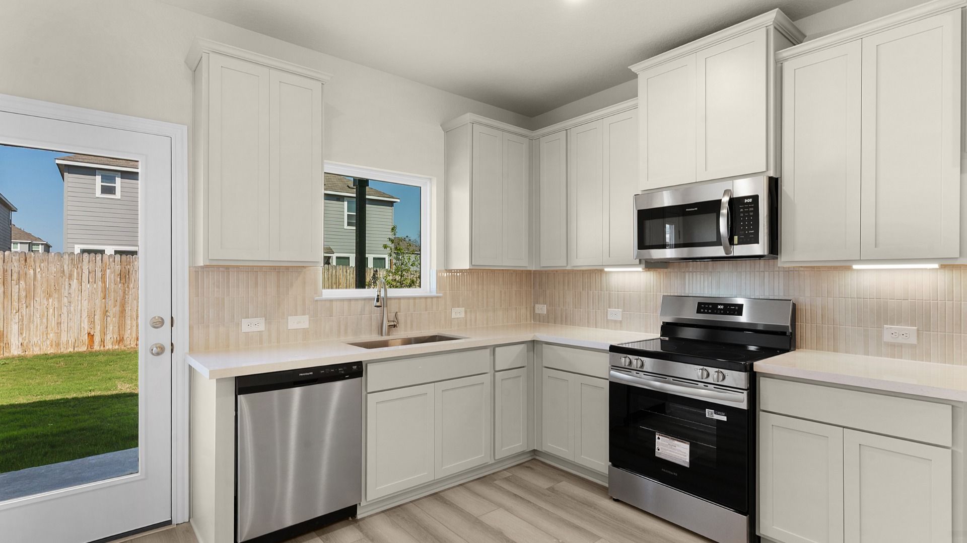 Kitchen featuring 42" painted cabinets, under cabinet lighting, and mosaic backsplash tile