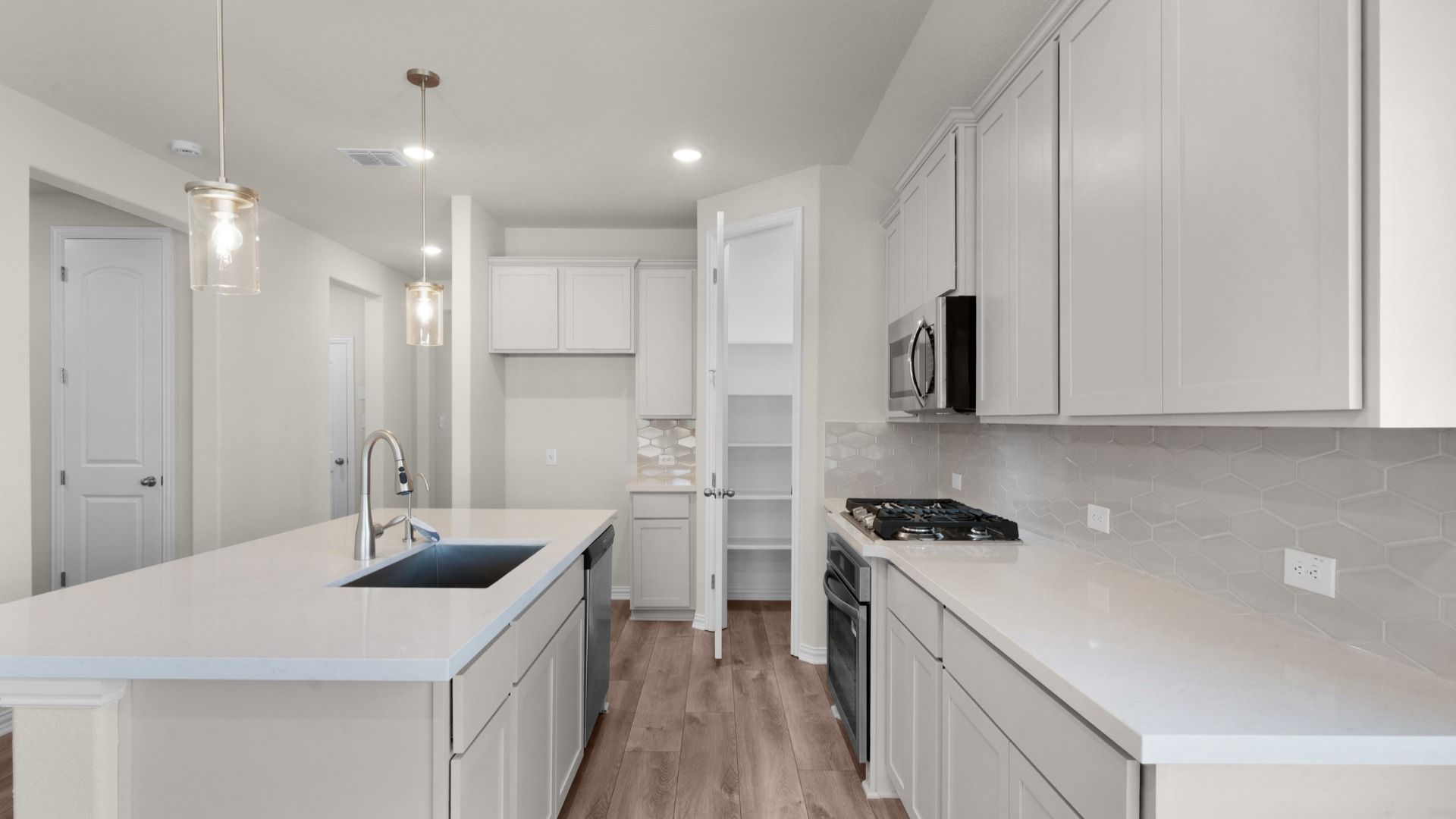 Kitchen featuring pendant lighting, corner pantry, 42" cabinetry,  center island, stainless steel gas appliances.