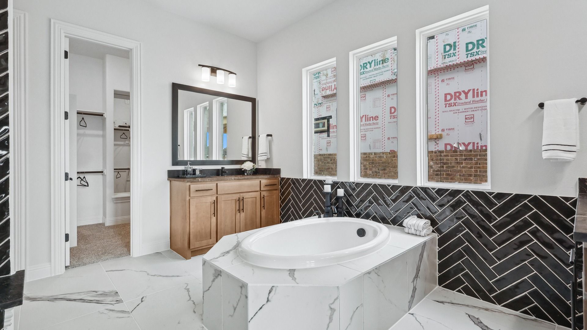 Elegant marble flooring and a chic herringbone backsplash define this exquisite Green Meadows bathroom.
