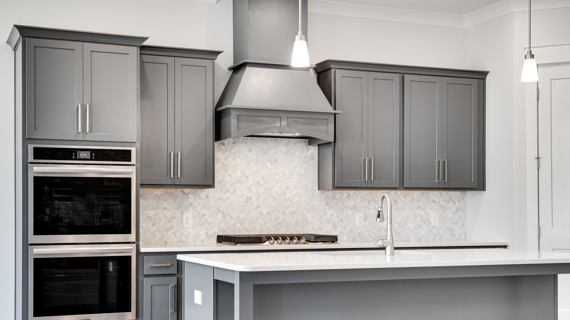 Kitchen with gray cabinets and modern style with tile backsplash and range hood