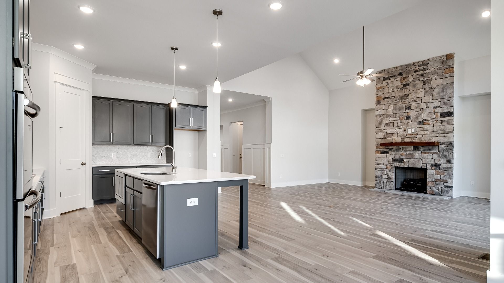 Kitchen layout with adjacent living room centered around stone fireplace