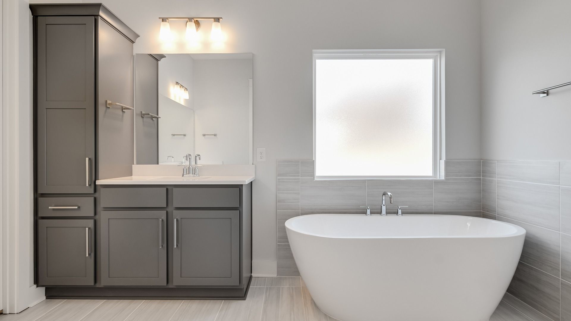 Large bathroom with freestanding tub and modern gray cabinetry and vanity