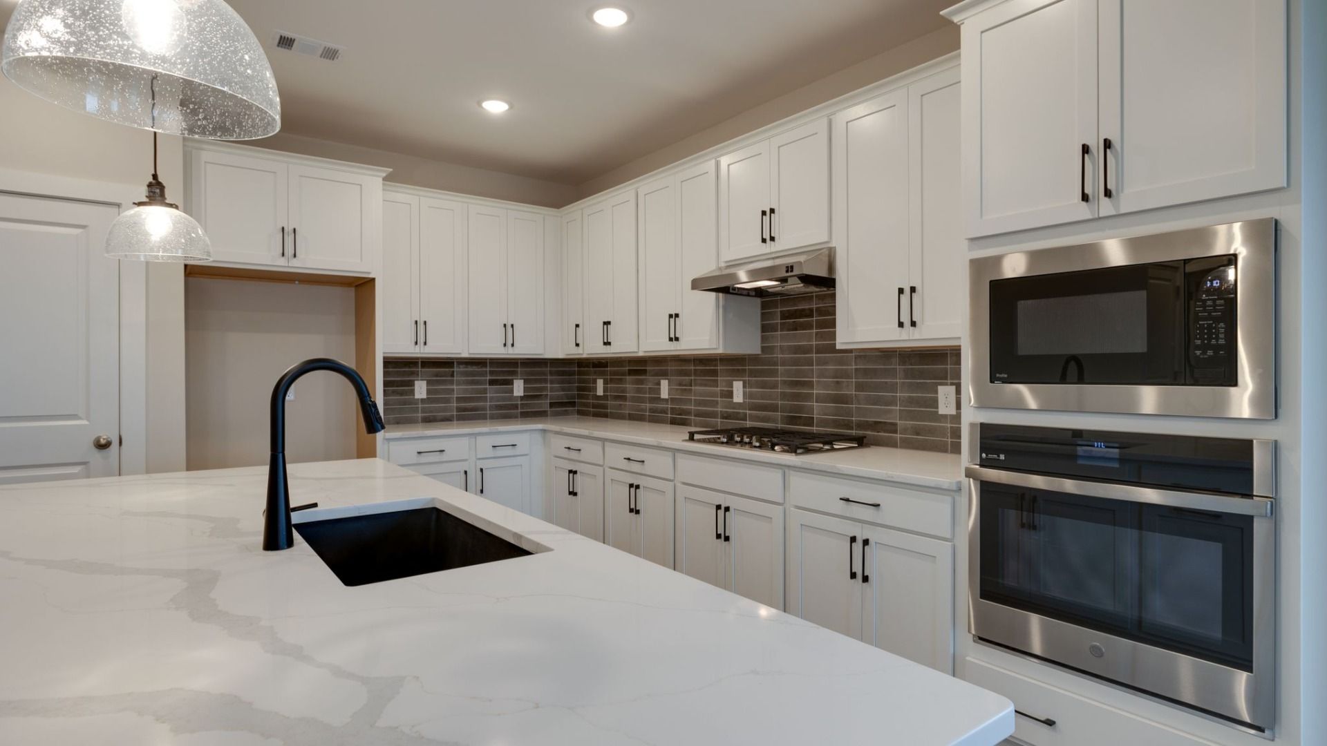 Kitchen with large island, accent tile backsplash, double wall ovens, pantry