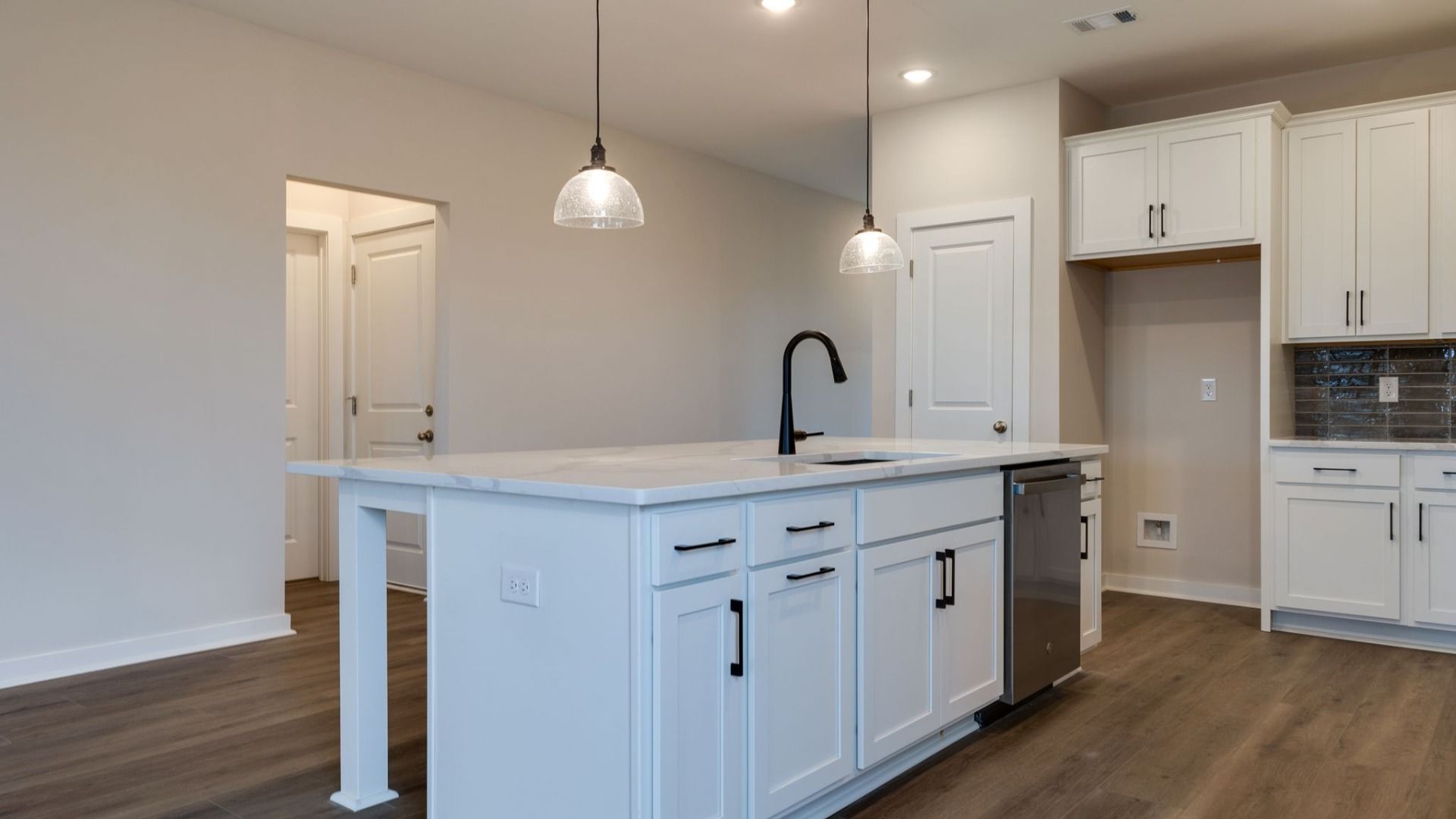 Kitchen with large island, accent tile backsplash, double wall ovens, pantry