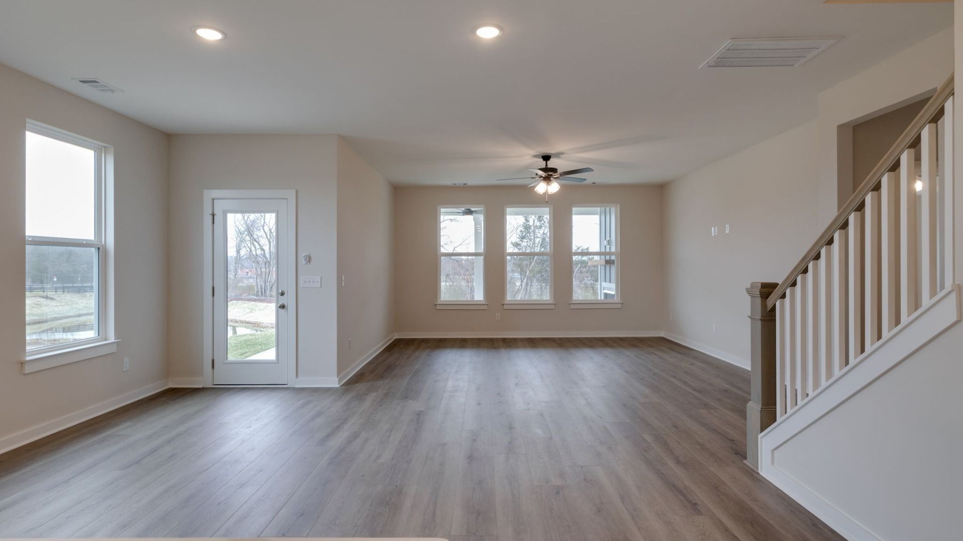 Open gathering room with large, bright windows and nearby bedroom