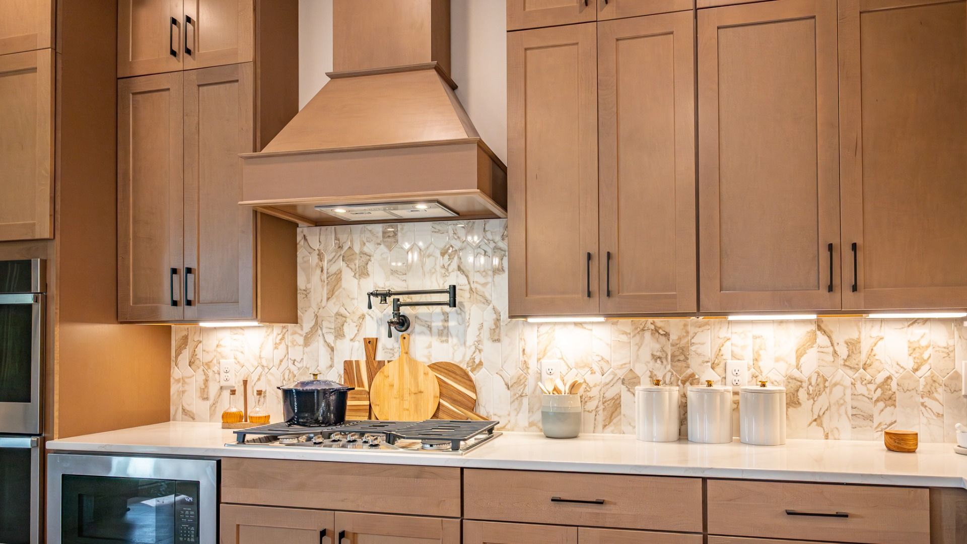 Kitchen with ceiling height natural colored cabinetry, pot filler, and gas range