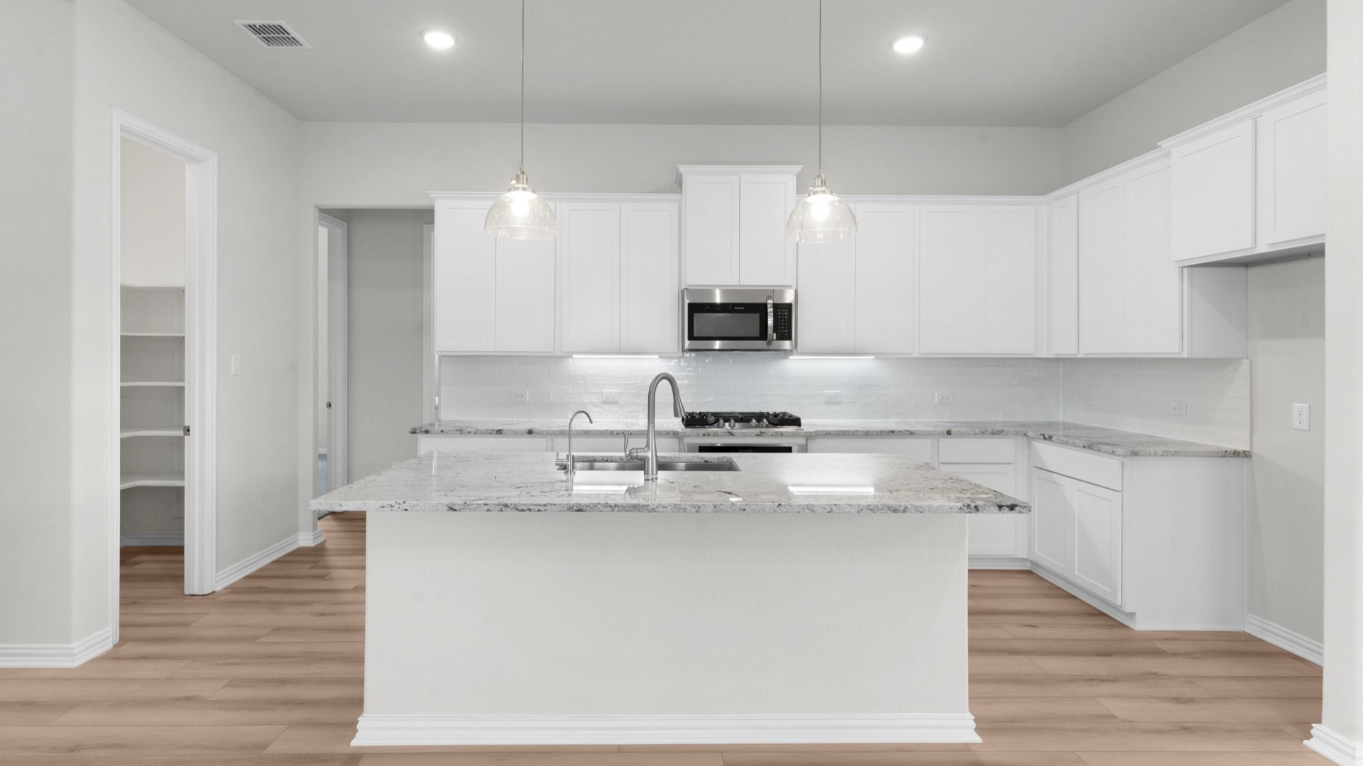 Bright kitchen with white 42” cabinets, gas cooking, granite countertops, and a large island