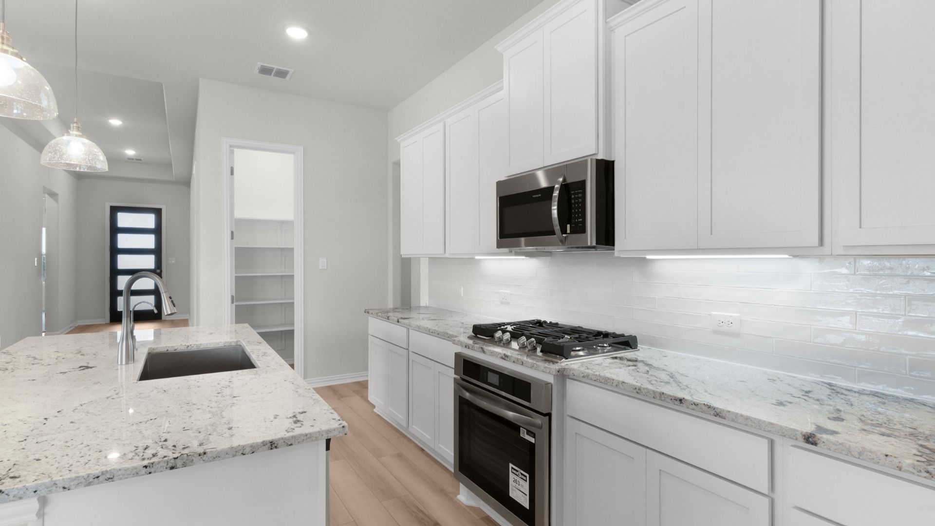 Bright kitchen with white 42” cabinets, gas cooking, granite countertops, and a large island