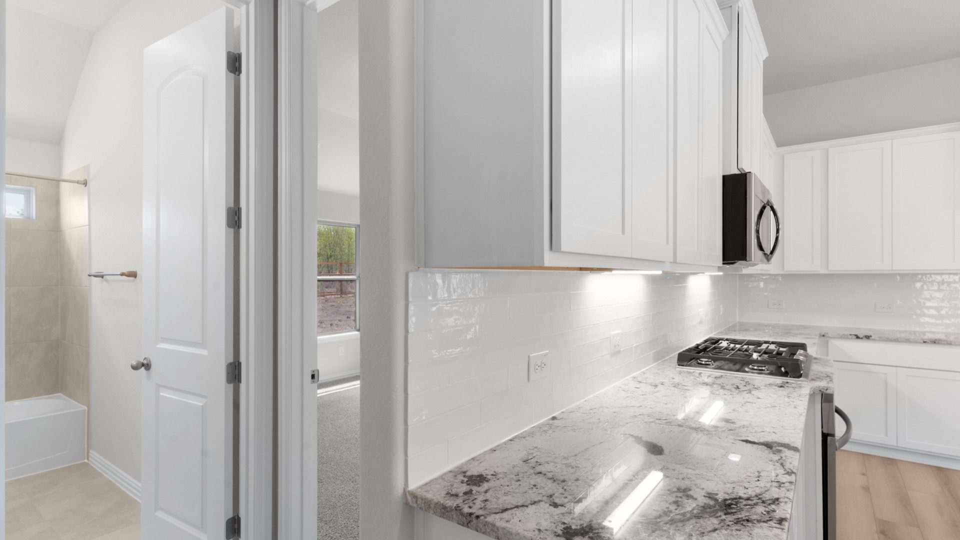 Bright kitchen with white 42” cabinets, gas cooking, granite countertops, and a large island