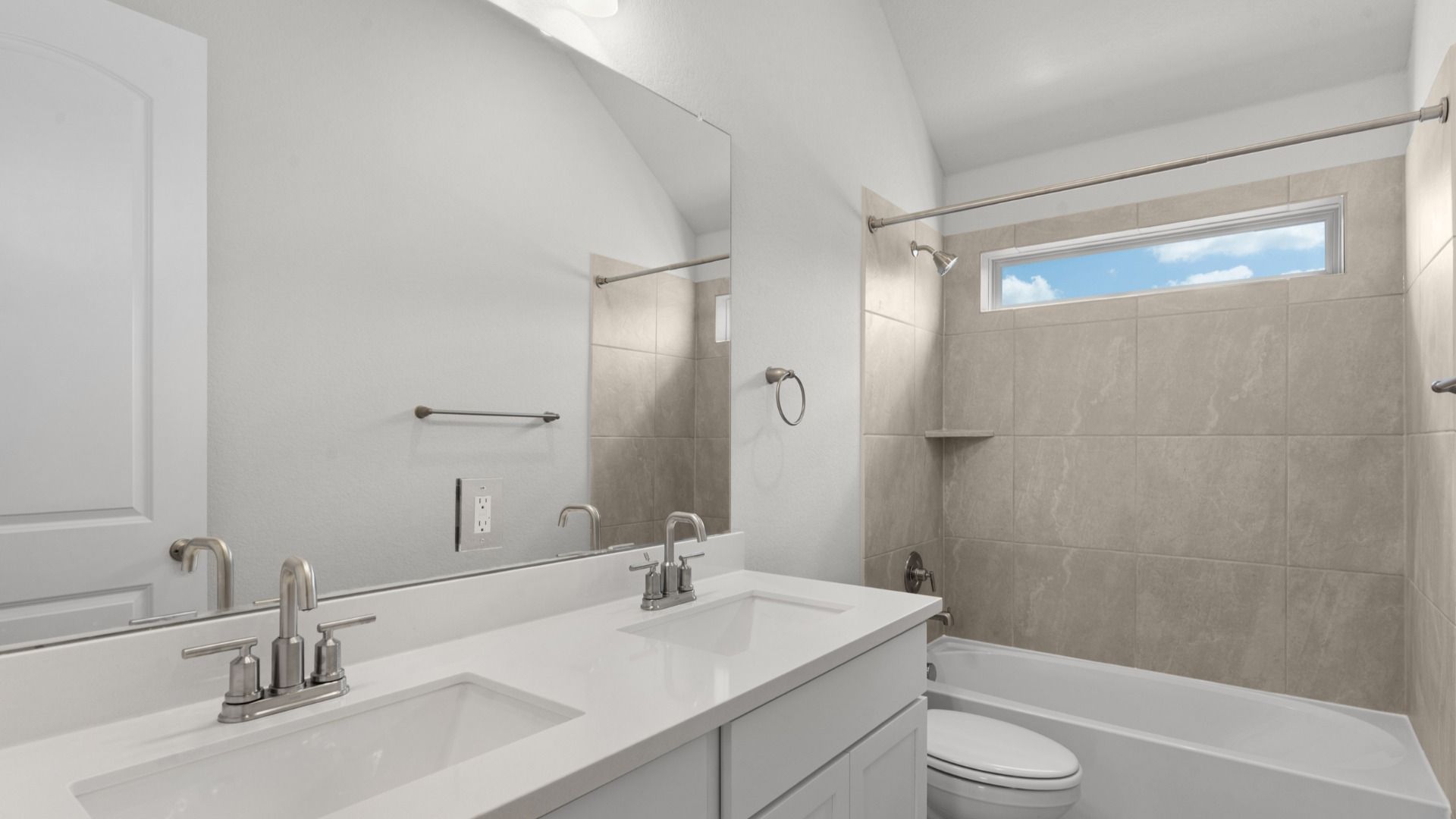 Clean and functional secondary bath with modern finishes and a window at the shower