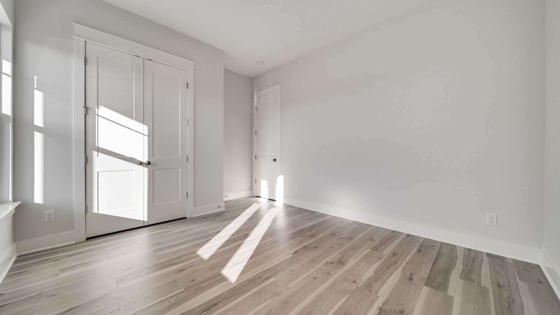 Secondary bedroom with hard-surface flooring and large windows with closet