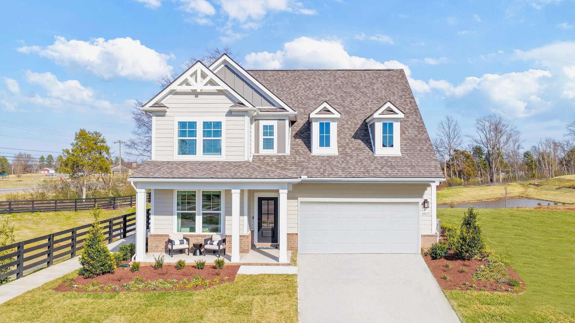 Exterior of home with neutral colored siding and brick accents with covered front porch and landscaping