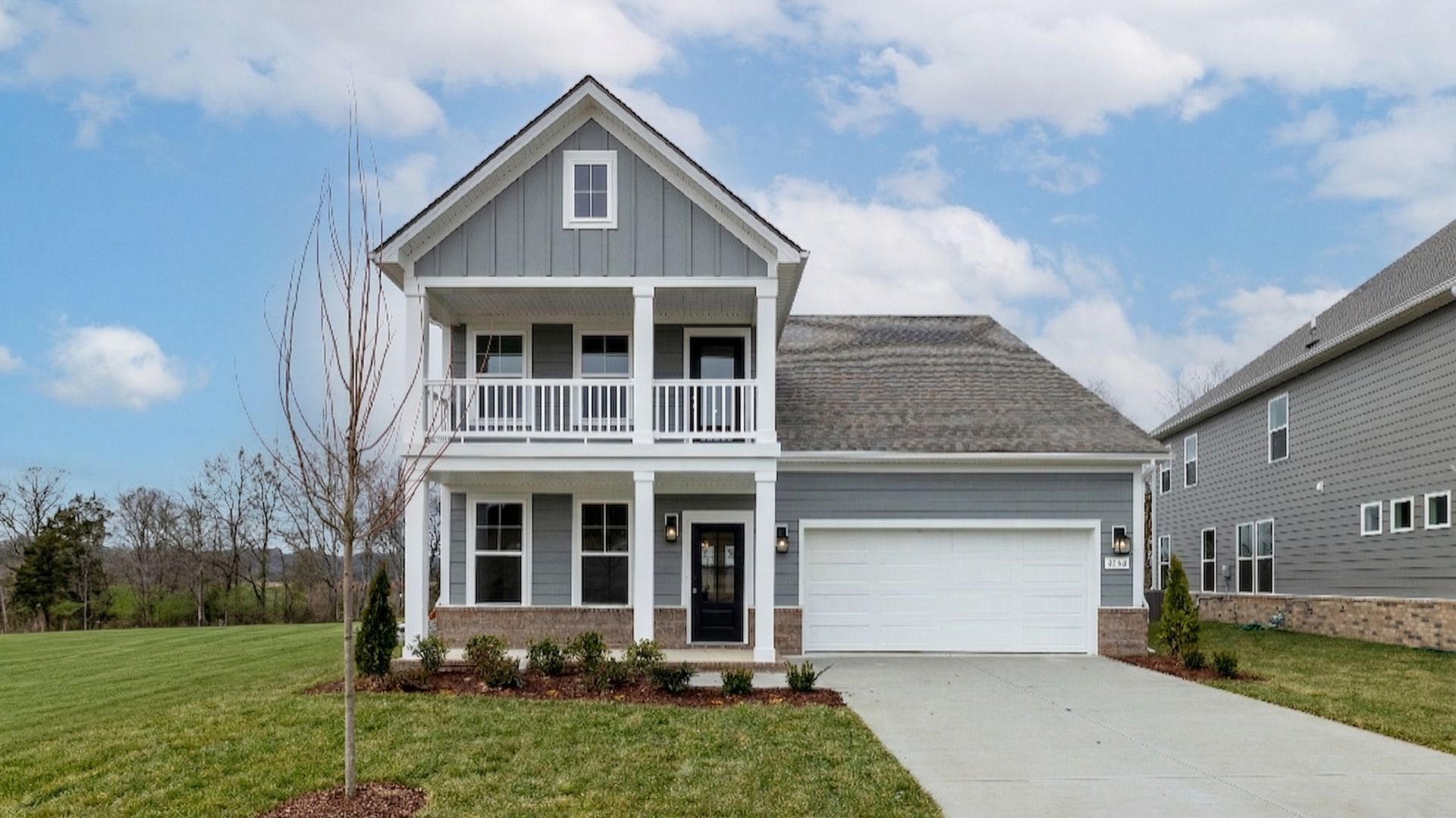 Exterior of home with blue siding and brick accents, with covered front porch and second floor balcony