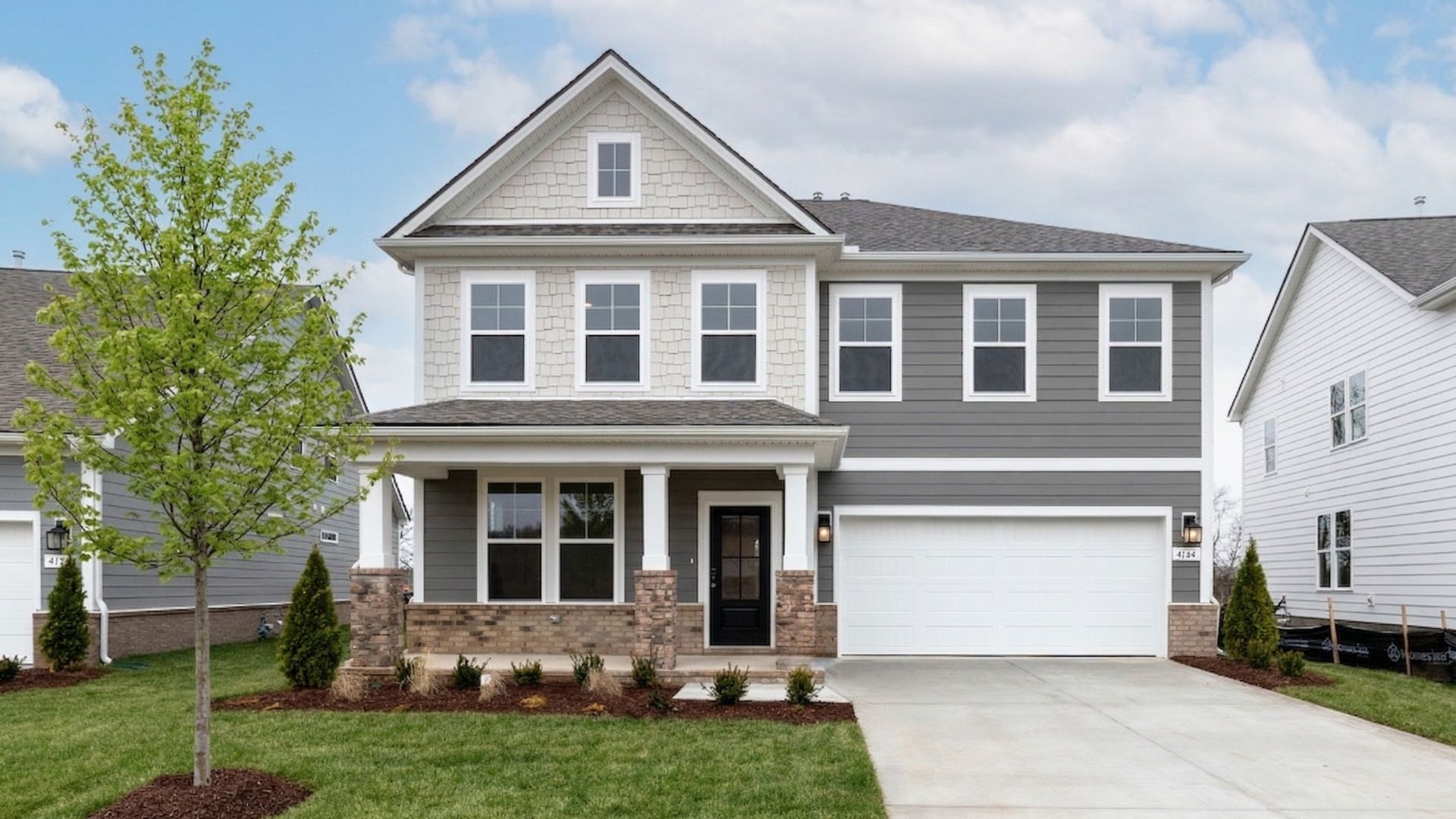 Exterior of home with two-tone siding with brick accents and columns around the covered front porch