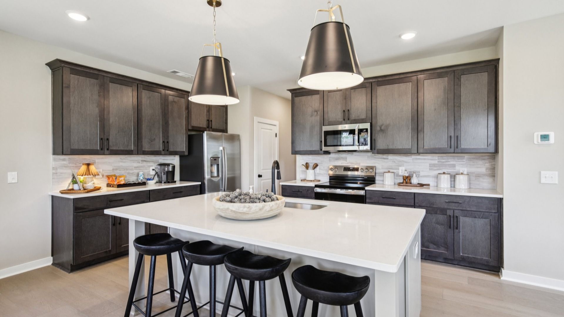 Kitchen with island, pantry, stained gray cabinetry, white quartz countertop, and light tile backsplash