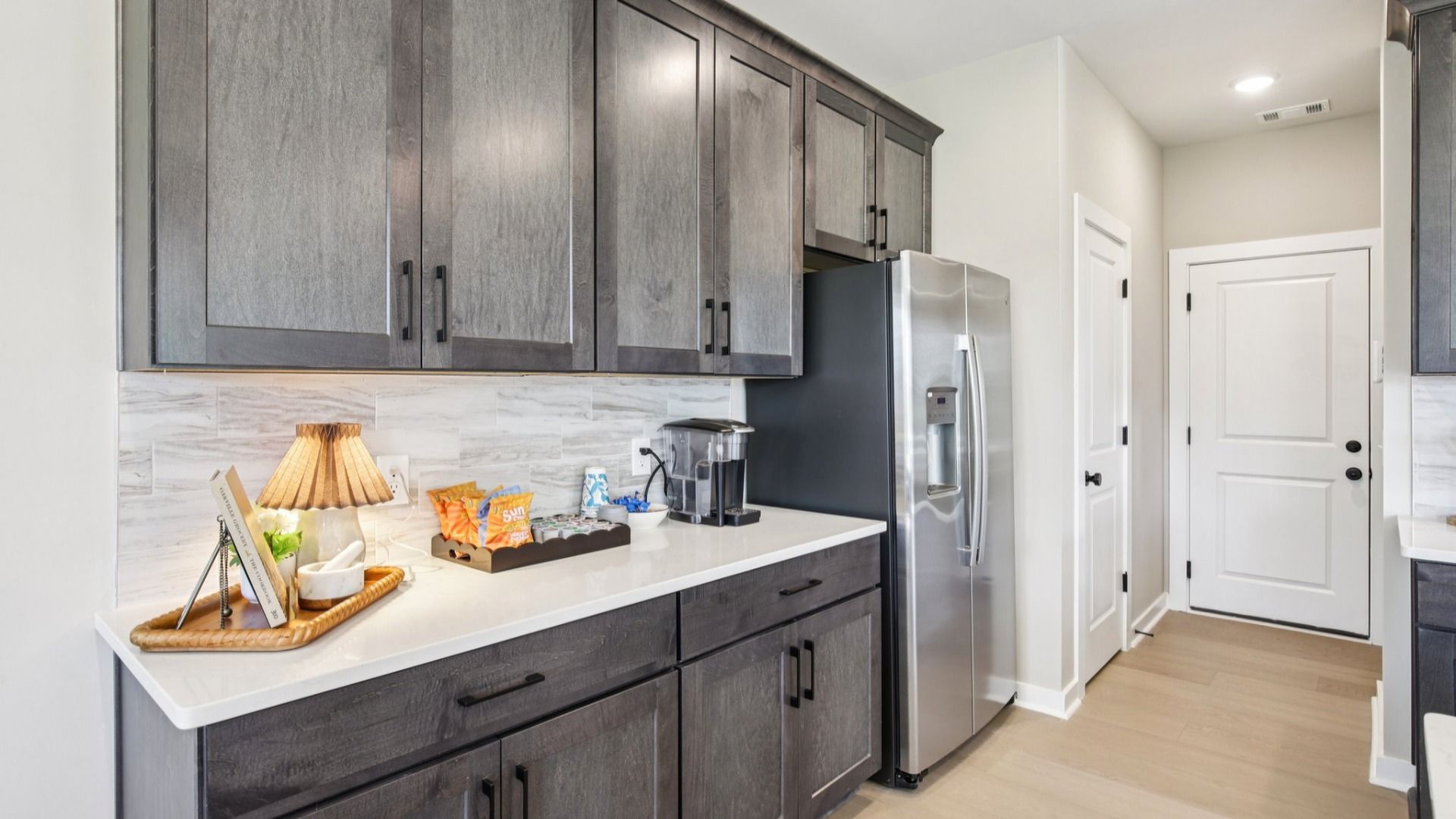 Kitchen with Pantry, stained gray cabinetry, white quartz countertop, and light tile backsplash