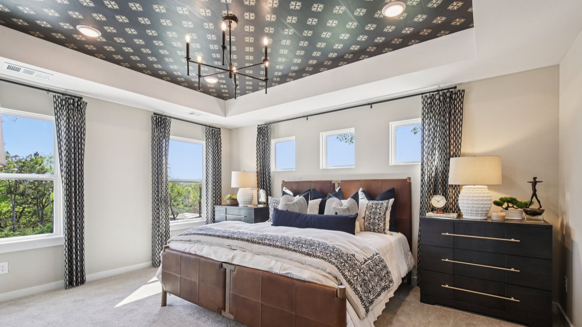Large primary bedroom with accent tray ceiling and multiple windows for natural light