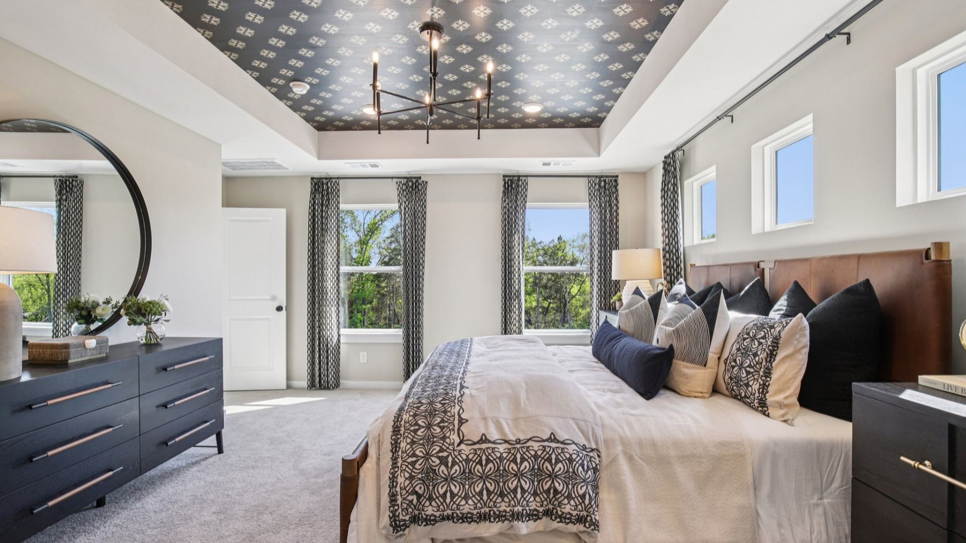 Large Primary bedroom with accent tray ceiling and multiple windows for natural light