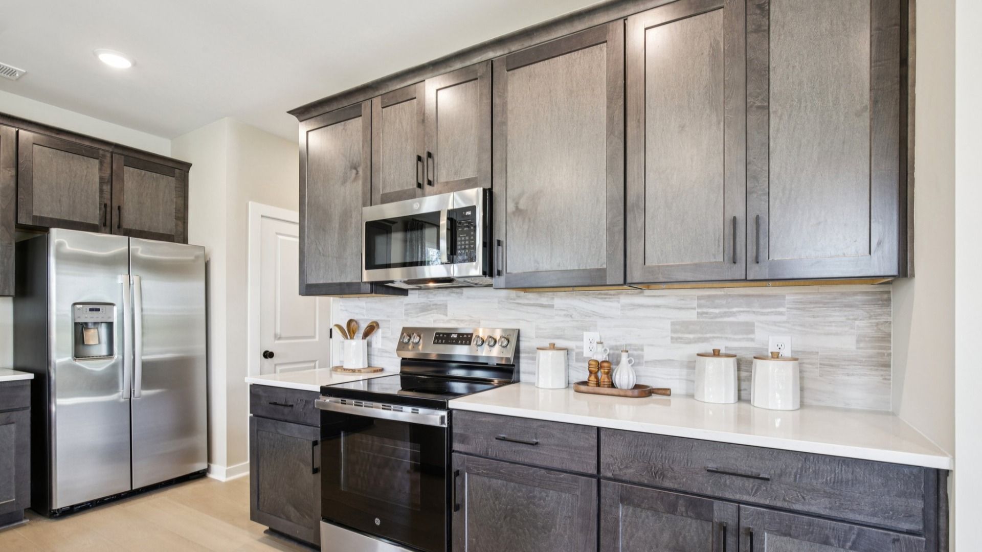 Upscale finishes including quartz countertops, stained cabinets, tile backsplash, and black hardware