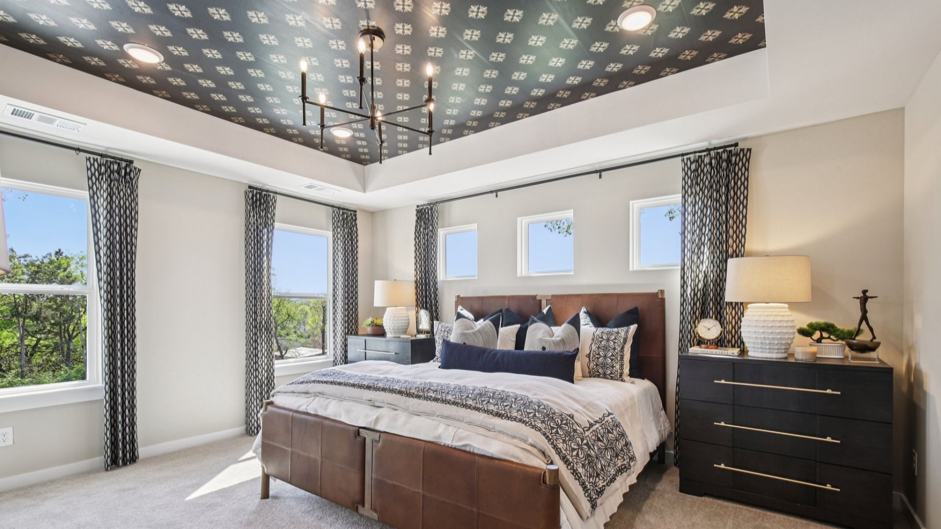 Large primary bedroom with accent tray ceiling and multiple windows for natural light
