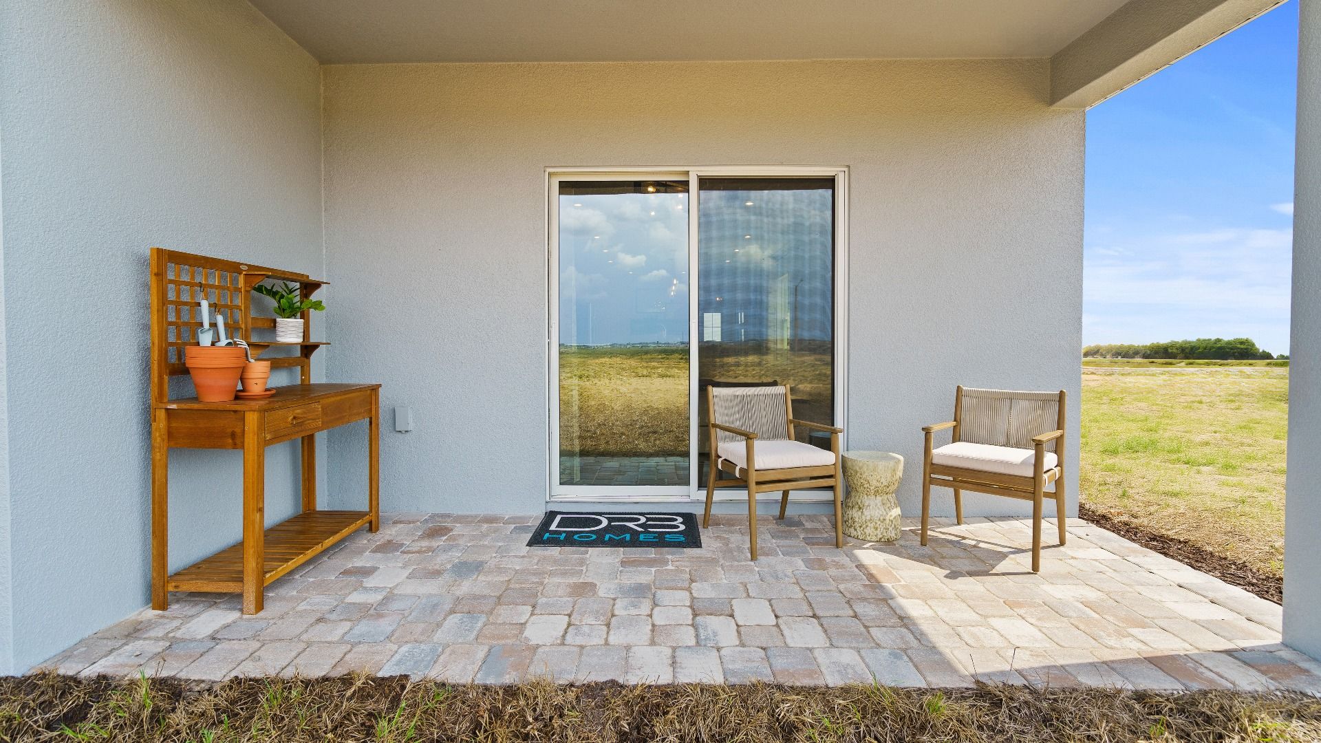 Atlantic Plan Single Story Home by DRB Homes, Rear exterior covered lanai staged with furniture.