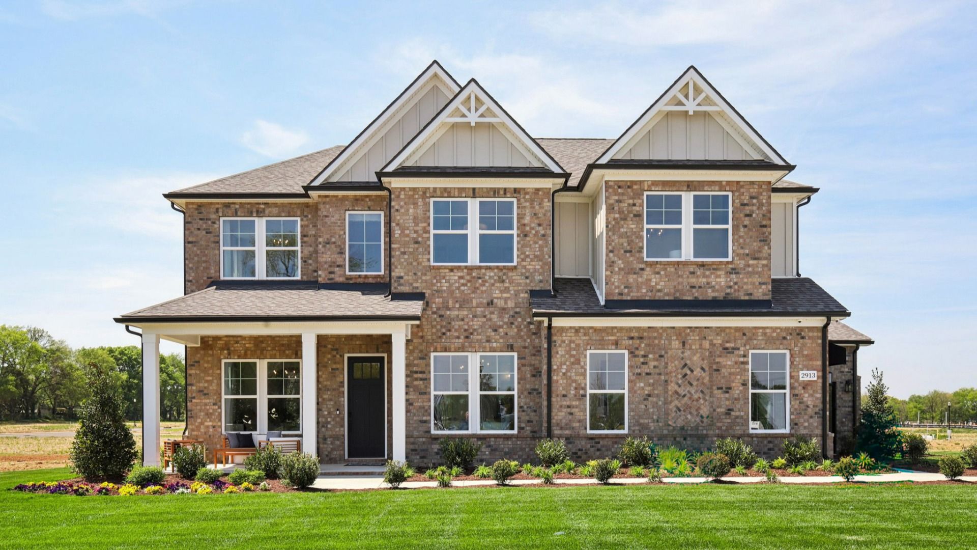 Full brick front on home with covered front porch and 3-car side-entry garage
