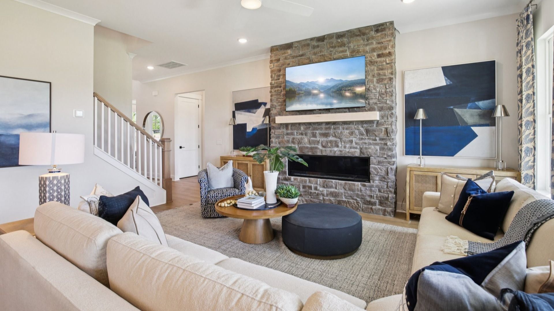 Large living room setup centered around stone fireplace with abundant natural light