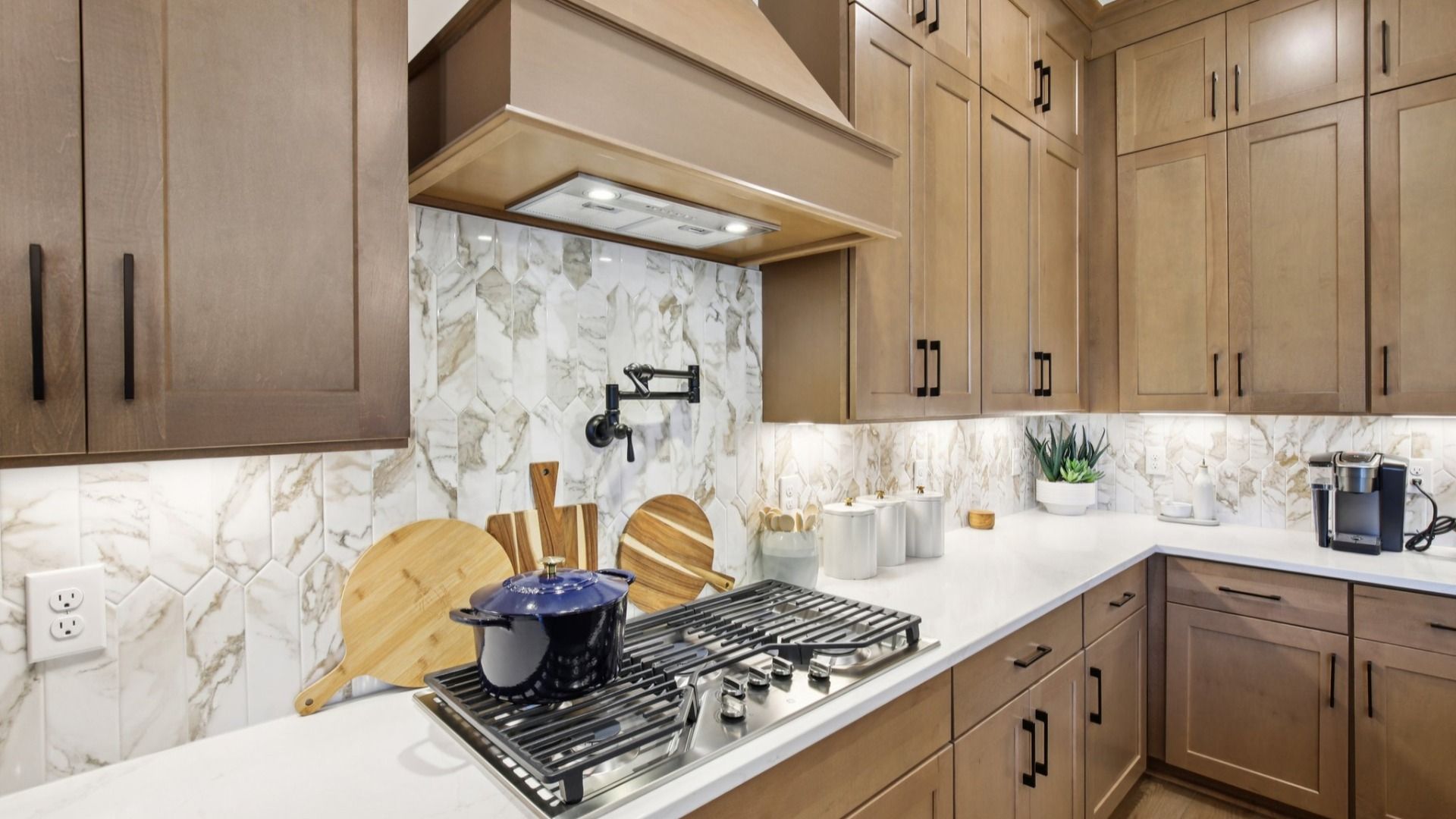 Kitchen with white quartz countertops, tile backsplash, and natural wood cabinets