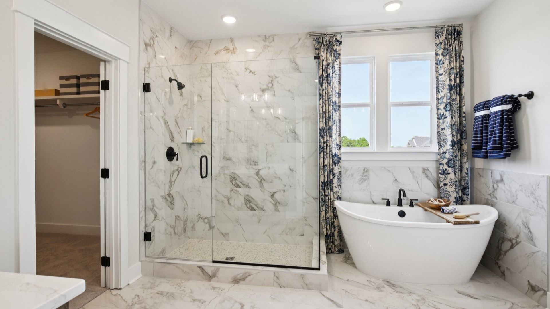 Large primary bathroom with fully tiled floor, shower walls, and freestanding tub surround